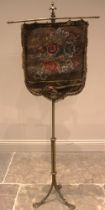 A Victorian gilt metal pole screen, with a needlework tapestry shield shaped banner screen, upon a