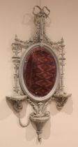 A 19th century painted gesso Adam style wall mirror, the oval mirror plate within an elaborate