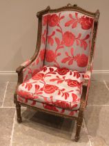 A French Louis XVI style wing back armchair, 19th century, re-covered in embossed red foliate