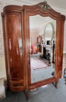 A French Louis XV style walnut triple wardrobe, early to mid 20th century, the cornice of break arch