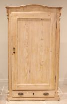 A Victorian pine hall cupboard, the arched and moulded cornice over a single panelled door opening