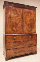 A George III mahogany linen press, with a moulded dentil cornice over a pair of oval banded doors,