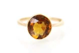 A 20th century citrine set ring, the round cut citrine with a rubover mount leading to plain