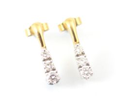 A pair of diamond trilogy earrings, the yellow metal stud suspending three graduated round cut