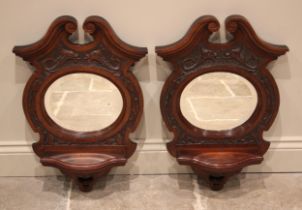 A pair of Victorian walnut mirrored wall brackets, each with a swan neck pediment over an oval
