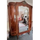 A French Louis XV style walnut triple wardrobe, early to mid 20th century, the cornice of break arch