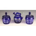 A near pair of blue flashed glass jars and covers, early 20th century, each with faceted