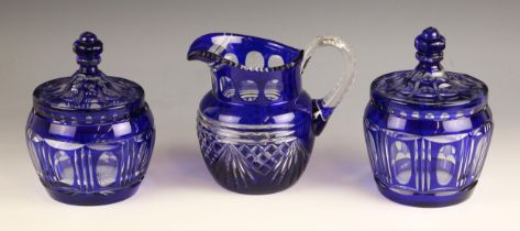 A near pair of blue flashed glass jars and covers, early 20th century, each with faceted