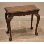 A George II style figured walnut games table, mid 20th century, the shaped and hinged top opening to