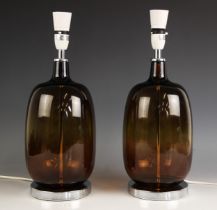 A pair of contemporary amber glass table lamps, of ovoid form, upon an integral chromed plinth base,