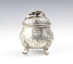 A continental white metal tea caddy, the cast foliate handle upon pull off cover above a bulbous