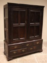 An 18th century oak livery/hall cupboard, the moulded cornice over a pair of quatre panelled doors