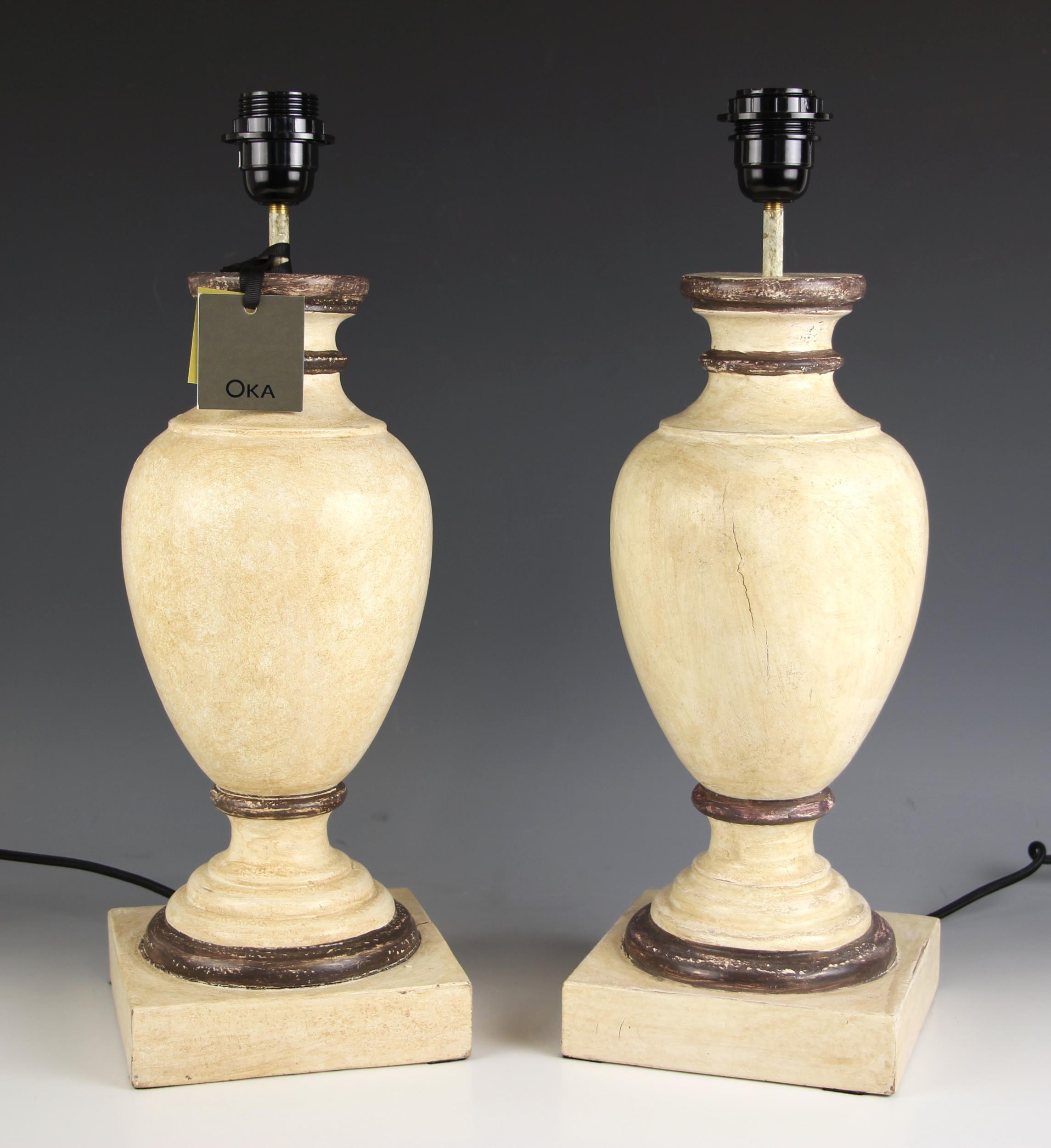 A pair of Oka 'Gela' wooden table lamps, of vase form, painted in ivory shades with brown detail,