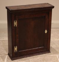 A George III oak spice cupboard, the single invert panelled door upon 'H' brass hinges, opening to