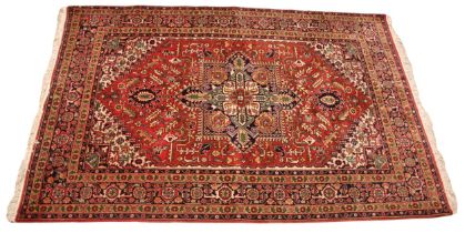 A Caucasian hand knotted wool rug, the central vibrant red field overlaid with a geometric medallion