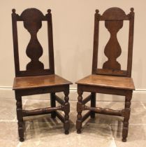 A pair of 18th century oak side chairs, the vase shaped splats above a board seat, upon block and