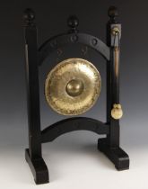 A brass dinner gong, 20th century, of planished form, supported by wooden frame, with beater, 68cm