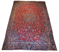 A large Turkish Mashad wool carpet, woven in a traditional medallion design in red and blue