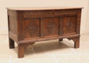 An 18th century carved oak coffer, the three plank hinged cover over a trailing foliate carved