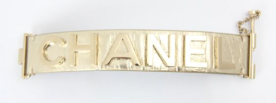 A Chanel leather bracelet, the light gold toned cuff with applied CHANEL lettering, with slide