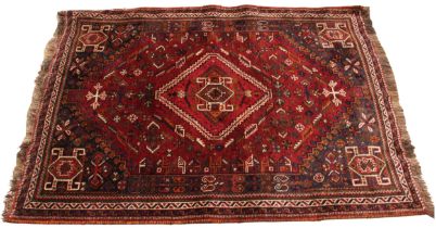 A Beluchi wool hand knotted wool rug, in red, green and blue colourways, the central geometric motif