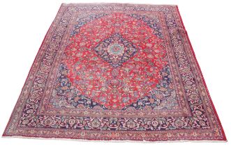 A Mashad wool rug, the vibrant red central field with a foliate medallion enclosed by conforming