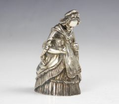 A 20th century white metal novelty table bell, modelled as a well-dressed lady holding a dog and