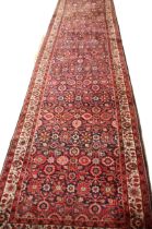 A Hamadan hand knotted wool runner, in red, blue and ivory colourways, the central field with an all