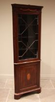 An Edwardian mahogany Sheraton revival freestanding corner cupboard, the moulded cornice over frieze