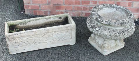 A reconstituted garden urn, of compressed campana form, upon a plinth moulded with a dolphins mask