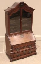 An 18th century Dutch walnut apprentice bombe bureau bookcase, the arched top with a carved crest