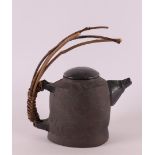 A gray ceramic teapot with braided wooden handle, collection Paul Mertz, h 24 cm.