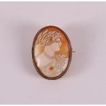 A brooch with a carved shell cameo in the shape of a female bust in 14 kt 585/1000 gold mount, 1st