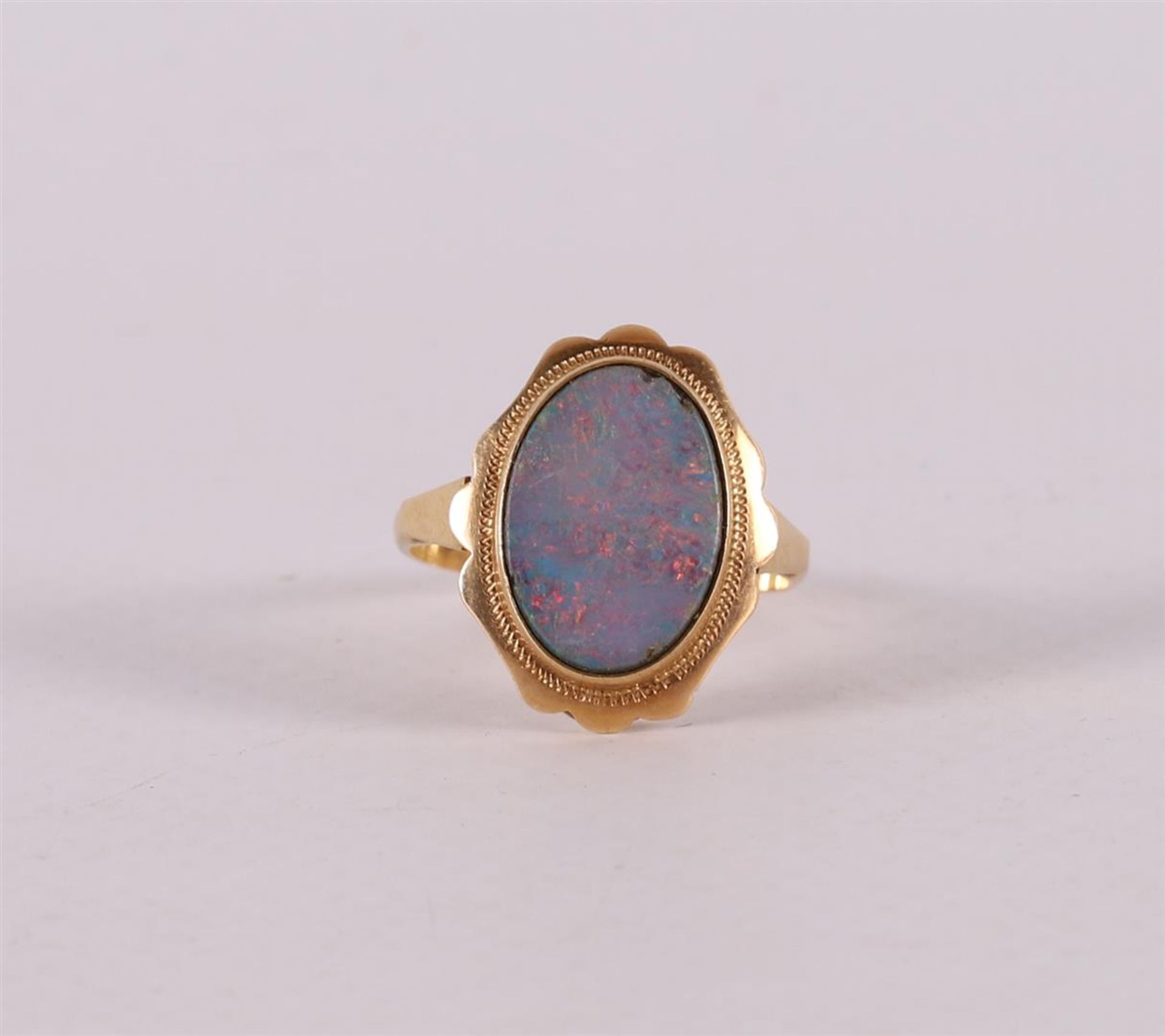 A 14 kt 585/1000 yellow gold entourage ring, set with cabochon cut oval opal, gross weight 3.9