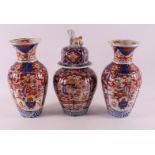 A three piece porcelain Imari garniture, Japan, Meiji, late 19th century. Consisting of: lidded vase