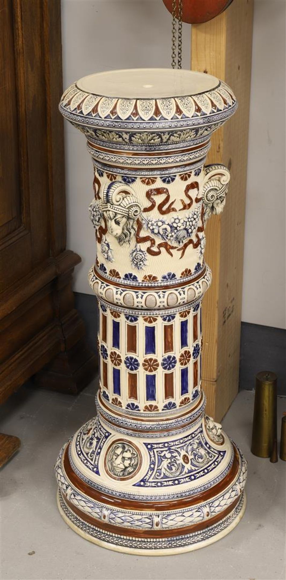 A cylindrical stoneware pedestal, Germany, early 20th century. Decor of ram heads, garlands and
