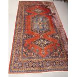 An Oriental carpet with red ground and geometric motifs, length 370 x width 235 cm.