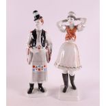 A pair of polychrome painted porcelain moldings of a man and woman in traditional Hungarian costume,