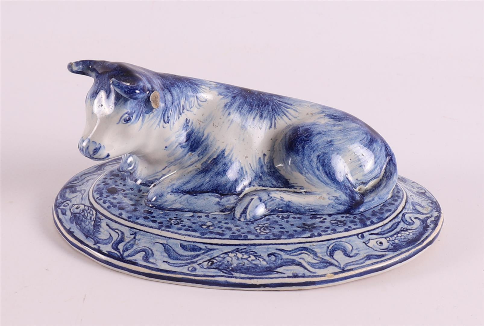 A blue/white pottery reclining cow, Holland, Makkum, Tichelaar, 20th century, h 6.5 x l 14 cm (