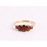 A 14 kt 585/1000 yellow gold row ring, set with faceted garnets, gross weight 1.4 grams, ring size