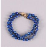 A 2-row bracelet of lapis lazuli beads with a hammered 14 carat 585/1000 gold clasp and a safety