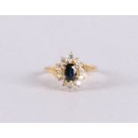An 18 kt 750/1000 gold ring with an oval faceted blue sapphire and an entourage of 12 brilliants