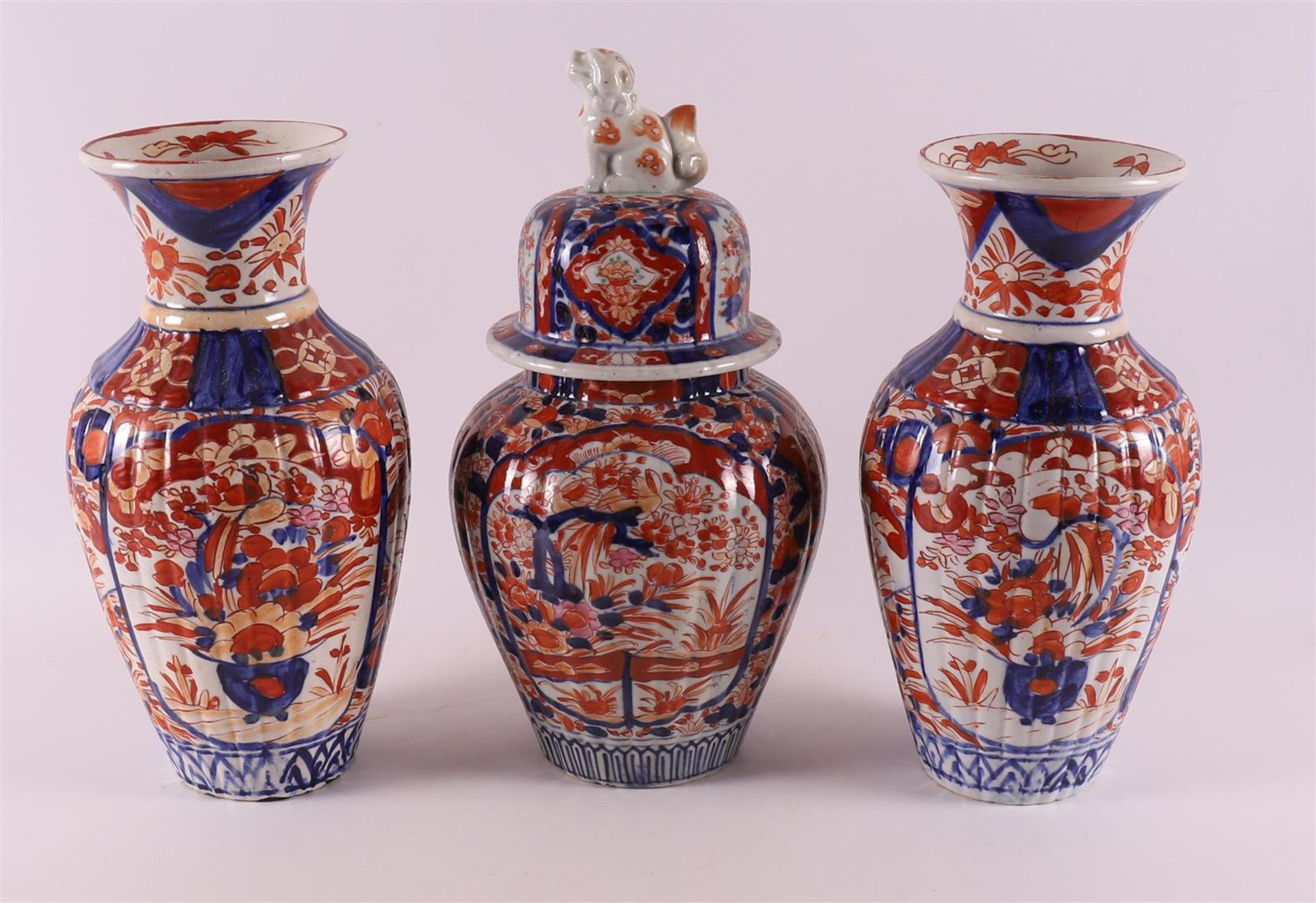 A three piece porcelain Imari garniture, Japan, Meiji, late 19th century. Consisting of: lidded vase