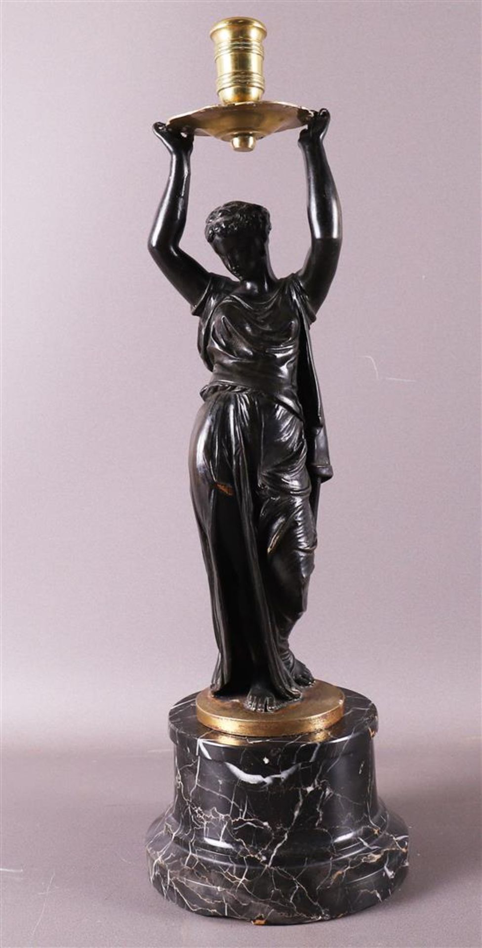 A bronze Greek woman with a candlestick above her head, after an antique example