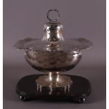 A silver Biedermeier tobacco jar with lid on wooden base, Holland, 1854.