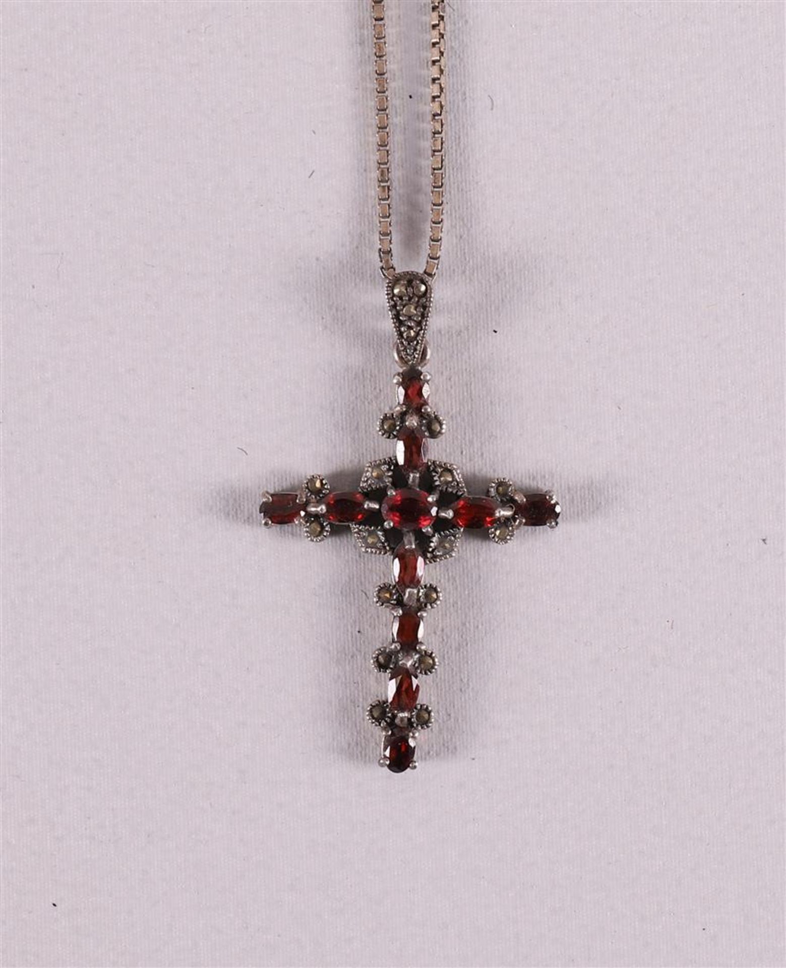 A silver necklace on a ditto silver cross pendant, set with garnets.