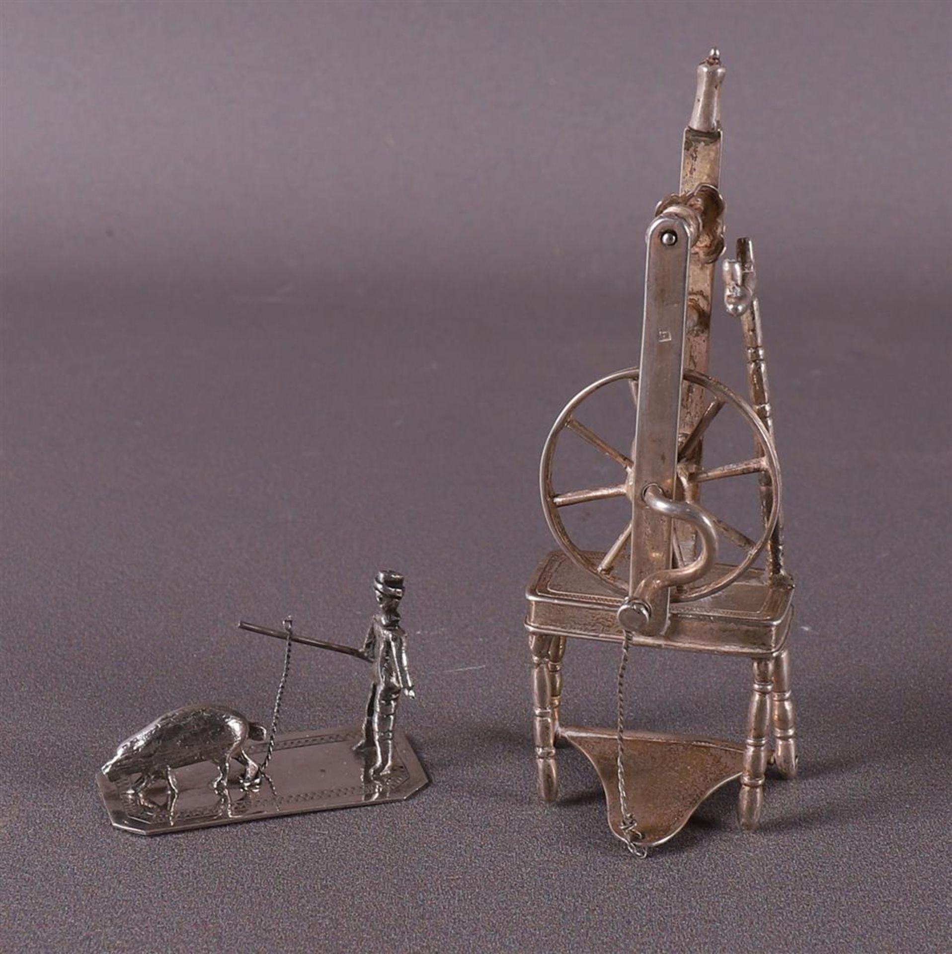 Etagere silver. A silver spinning wheel + Farmer with pig, 20th century.