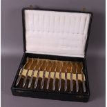 A gilded breakfast cutlery with silver handles, in original case, around 1900.