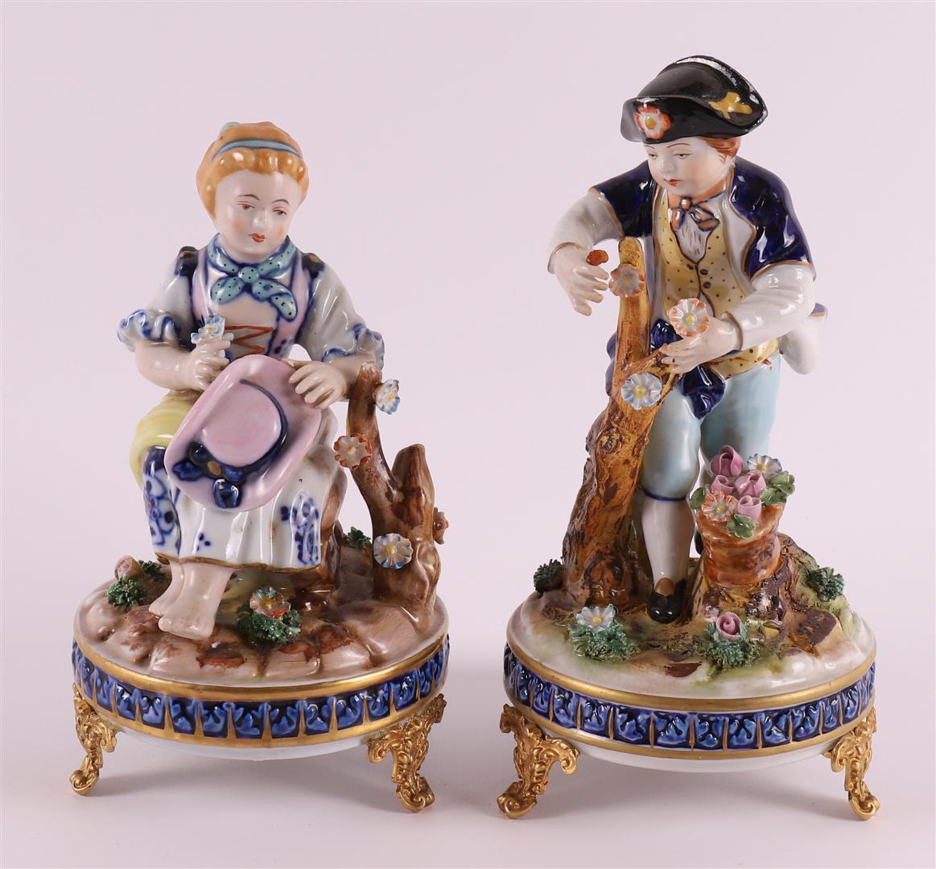 A pair of polychrome porcelain sculpture groups of a young man and young woman, France, probably