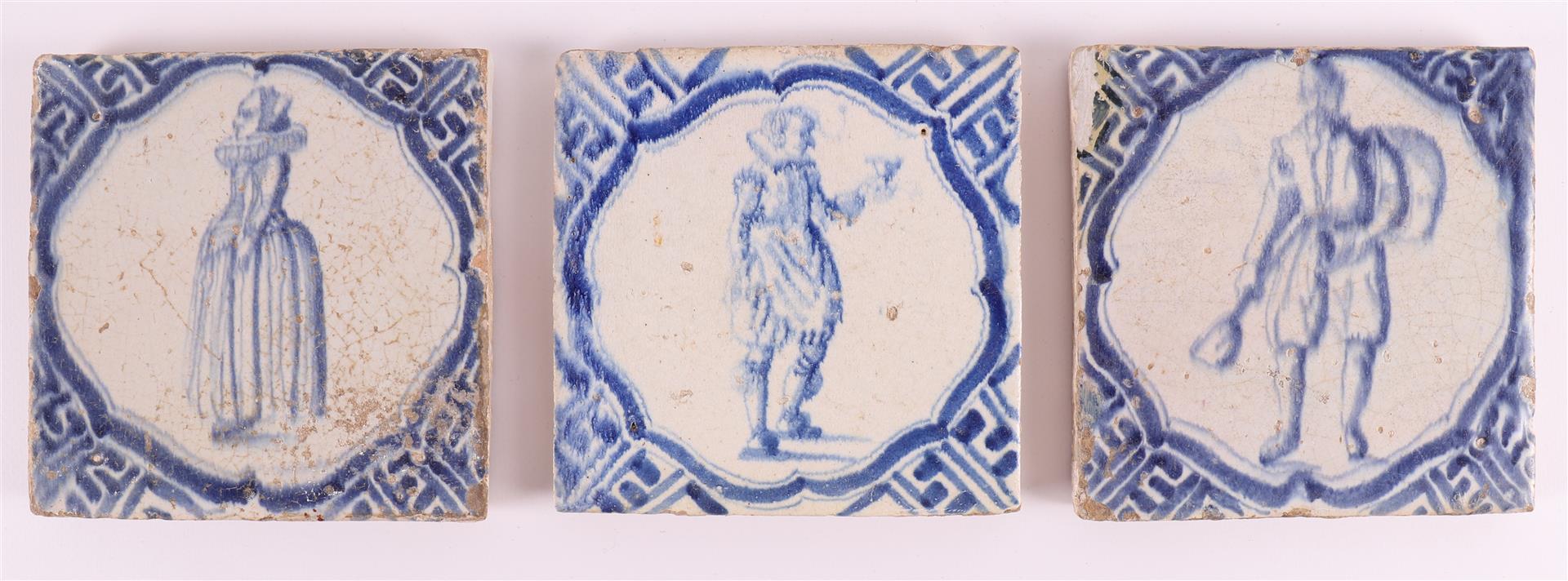Three various blue/white tiles with, among other things, an image of a man with a bird and a woman